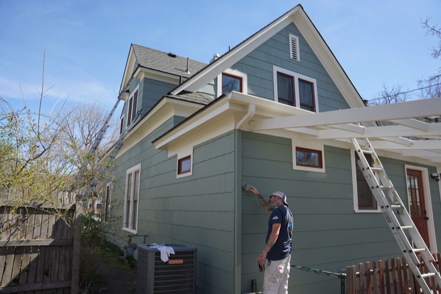 Painter brushing exterior siding trim on a home in Mountain Grove, MO